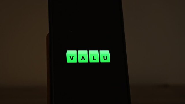 Bright green cubes spell VALUE across a smartphone screen in a dim room, glowing against the black display. Suits value proposition, customer value, investment value, core values and worth for money 