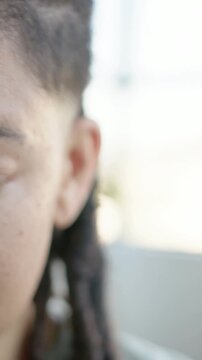 Vertical video: Framing shifting, woman with braids pulling back and smiling by window, copy space