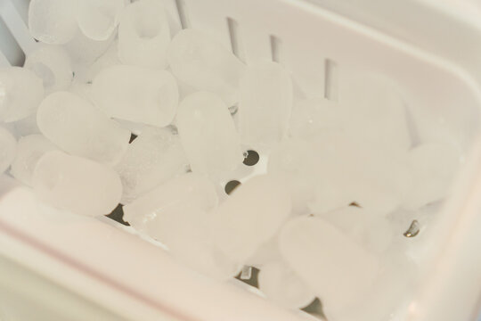 A close-up of cylindrical ice cubes inside a white ice maker basket. Represents ice production, cooling equipment, cold beverages and restaurant service.