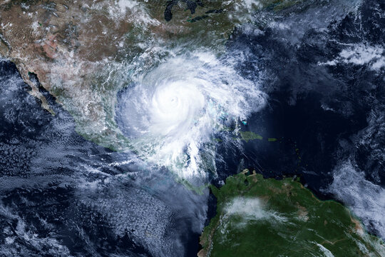 Satellite view of a massive hurricane spinning over the Gulf of Mexico, featuring a clear eye, swirling white storm clouds, and dramatic atmospheric perspective over Central and North America. Isaias