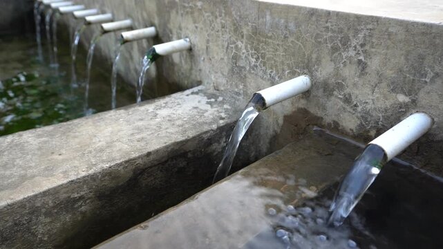 Fresh clean mountain water flowing from PVC pipes distribution hub system in Mount Muria rural village area, Central Java, Indonesia, providing pure natural stream water for local residential homes.