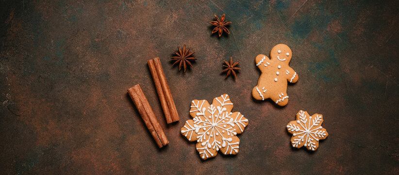 Gingerbread man and snowflakes on dark rustic background, top view, flat lay