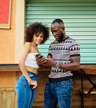 Portrait of two young people a couple using a phone taking a selfie with a smartphone in the street