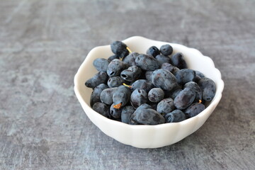 Bowl of Fresh Dark haskap Berries on Gray Textured Surface, copy space © Irina