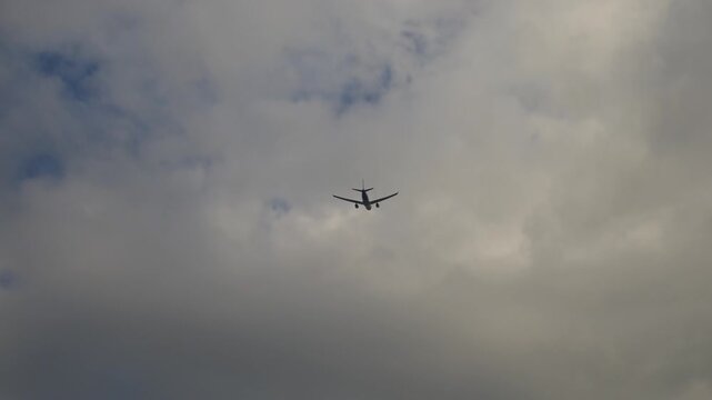 The airplane flies through the sky and moves away from the camera