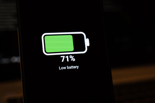 Green battery icon at 71 percent with an ironic Low battery label on a dark smartphone screen, concept of battery anxiety, misleading notifications, software glitch and humor about phone charging hab