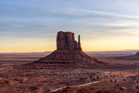 The West Mitten Rock Formation in Monument Valley Arizona At Sunrise With a Yellow and Orange Sky
