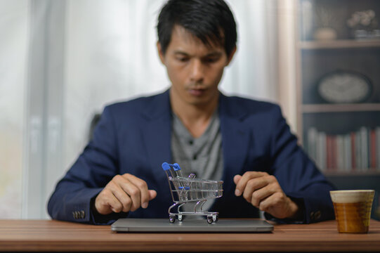 Businessman in a blue suit playing with a miniature shopping cart on a desk