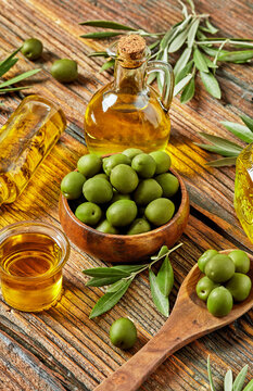 Fresh green olives, olive oil and rustic wooden table setting