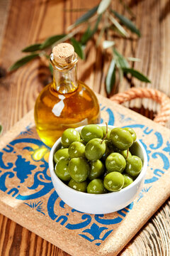 Fresh green olives and olive oil on rustic wooden table