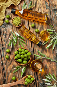 Olive oil bottles, green olives and wooden bowls arranged overhe