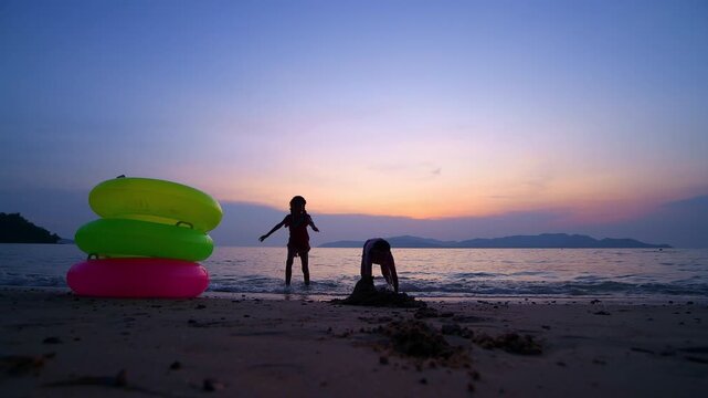 Children playing brightly colored inflatable rings joyful at the beach during playful and enjoying funny of summer semester vacations .