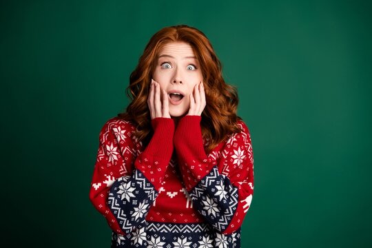 Surprised young woman in a festive Christmas sweater expressing shock and holiday excitement against a green background