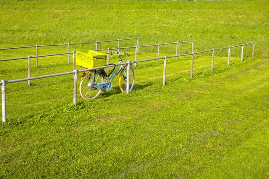 green grass field en bicycle leaning against a wooden bike rack