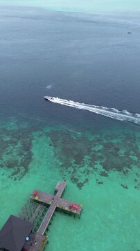 Aerial view speedboat over turquoise reef at Derawan Island pier
