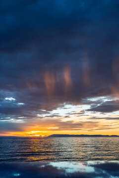 Scenic sunset over the sea with dramatic dark clouds and warm light on the horizon