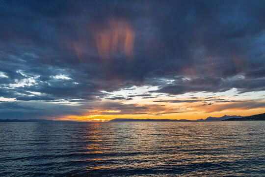 Scenic sunset over the sea with dramatic dark clouds and golden light reflecting on the water surface