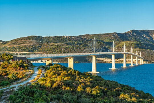 Peljesac bridge crossing the bay with blue sea and green hills in Croatia