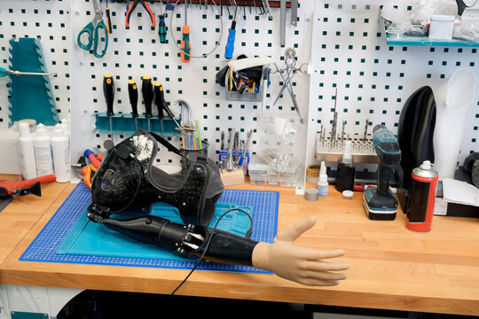 Carbon fiber prosthetic arm and artificial hand displayed on a workbench.