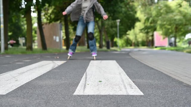 Young girl with blonde hair inline skates on a paved park path during daytime.