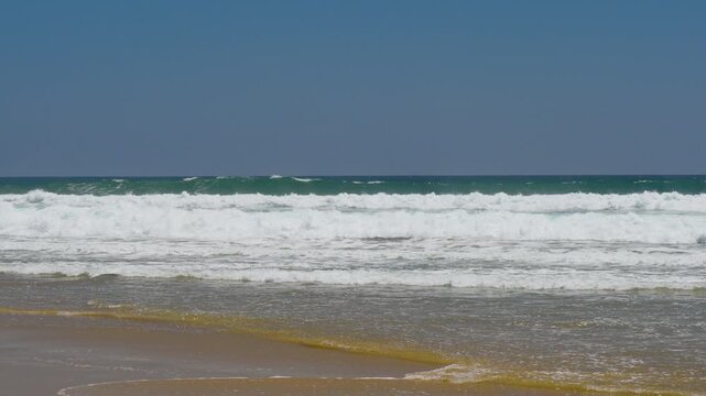 Wide shot of large waves breaking on the beach in California