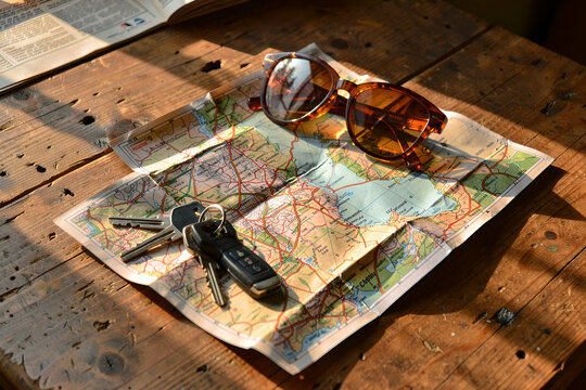 Still life with folded map, keys and amber sunglasses on weathered wood