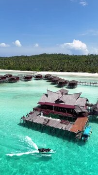 4K vertical aerial overwater bungalows resort Maratua Island with boat