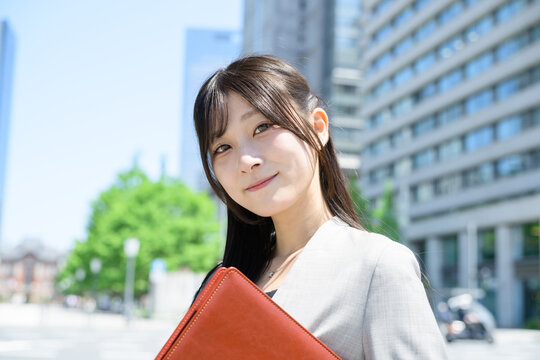 ビル街でバインダーを持つ日本人女性