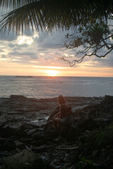 Woman watching the sunset from the rocks on a tropical beach in Puntarenas, Costa Rica © Julin