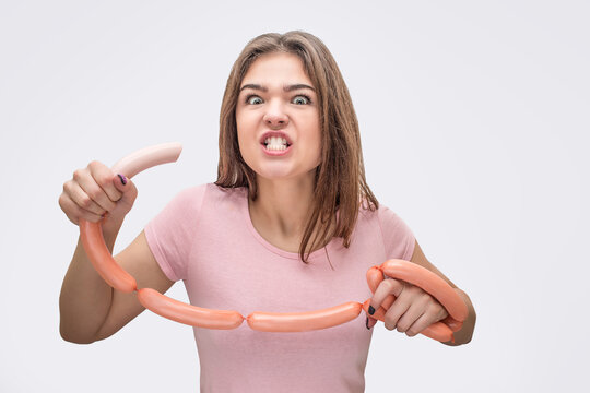 Man and angry young owan look on camera with sausage in mouth. She look on camera. Model hold set of sausages. Isolated on white background.