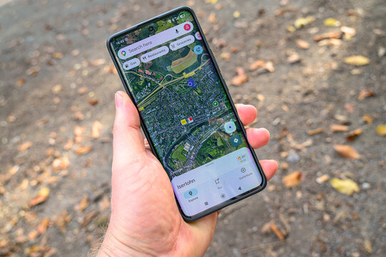 Iserlohn, Germany - October 03, 2026: Hand holding a smartphone displaying the Google Maps application with satellite view outdoors
