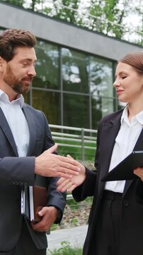 Professional man and woman business partners having a business discussion while reviewing information on a tablet, followed by a handshake. Slow motion