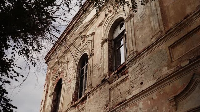 Weathered old building facade with arched windows and tree branches