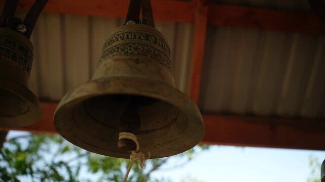 Two bronze church bells hanging under a wooden roof