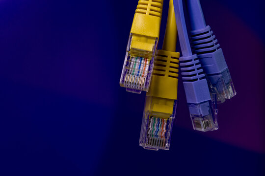 Four Ethernet cables with yellow and blue connectors displayed against a dark blue background, representing networking technology and data communication.