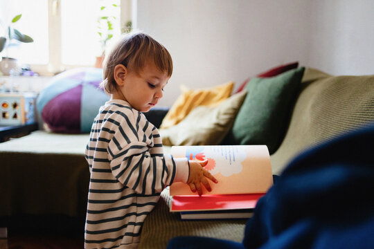 Toddler Reading a Colorful Book on a Couch at Home