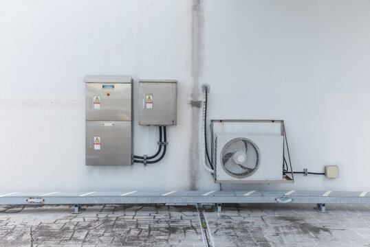 Air Conditioner Unit and Electrical Boxes on Building Wall