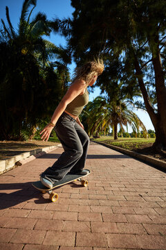 Surfskating down a path lined with trees in the afternoon