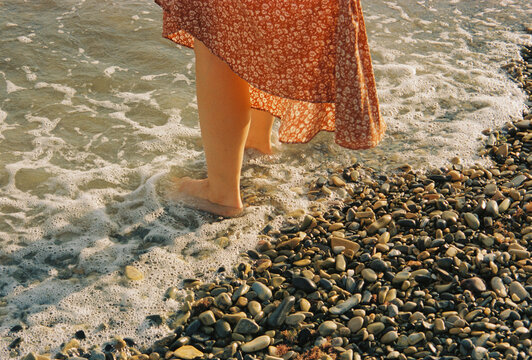 Foam rushes over bare feet on a rocky coastline