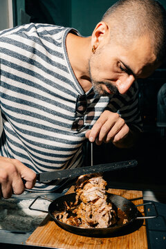 Man Prepares Meat in a Kitchen During Evening Time