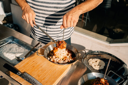 Man Prepares Food at Outdoor Kitchen During Sunny Afternoon
