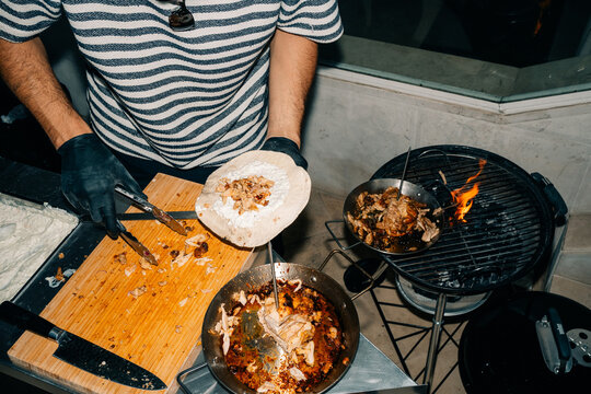 Cook Prepares Food at Outdoor Grill With Meat and Tortillas