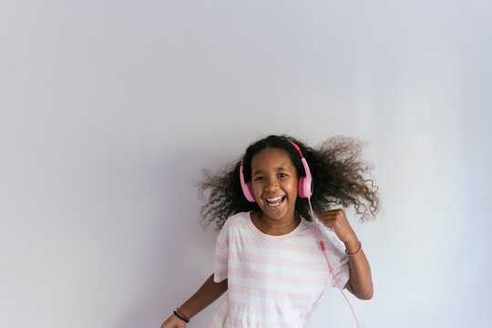 Joyful Girl Listening to Music with Pink Headphones