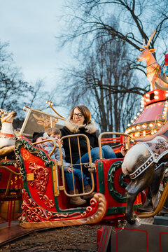 Mom and son have fun on the carousel in the Amusement park
