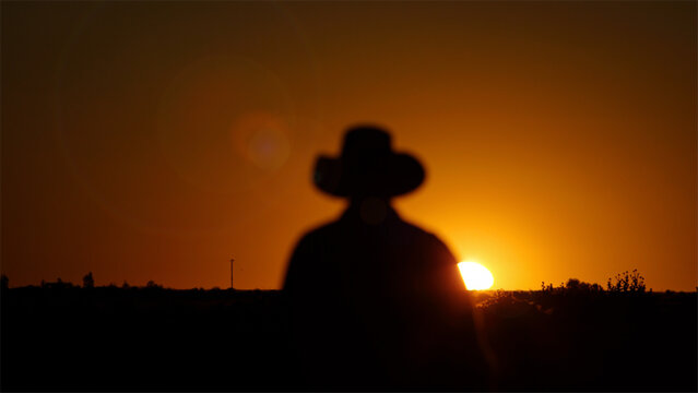 Outback farmer, bush hat, sun silhouette in dry hot El Nino drought