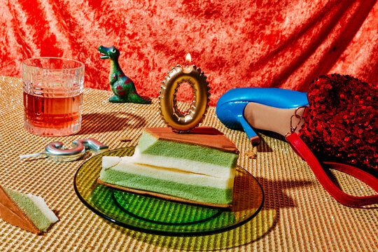 a lit zero candle on green cake with a silver five lying nearby