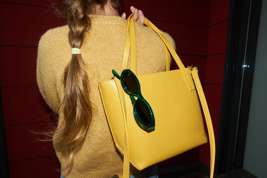 Back of a woman holding yellow bag with sunglasses