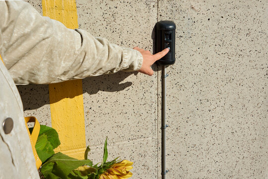 Person pressing a button on video doors intercom