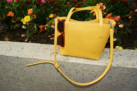Yellow bag with sunglasses against colorful flowers. Flash