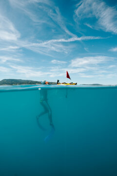freediver next to a buoy in a wide split-level view